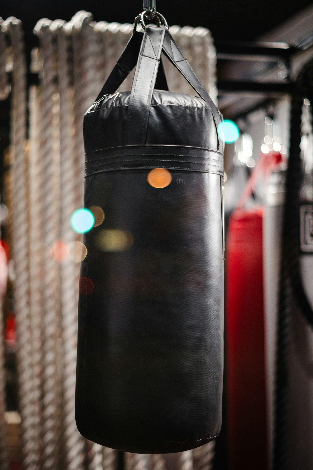 A heavy punching bag hanging from a chain in a dim boxing gym.